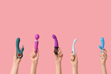 Female hands with different vibrators on pink background