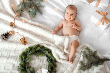 Cute little baby with Christmas gifts and decor lying on white blanket, top view