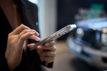 Woman in stylish dress with chic manicure using smartphone in closeup shot