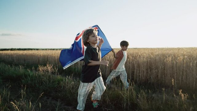 Australian little boys - sons patriots with national flag on sky background at sunset. Australia celebration banner, Anzac day, commonwealth