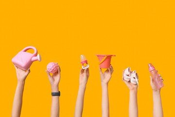 Female hands with baby accessories and toys on yellow background