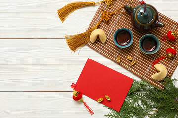 Blank card with cups of tea, fortune cookie and Chinese symbols on white wooden background. New...