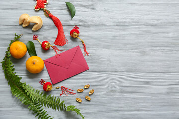 Envelope with tangerines, fortune cookies and Chinese symbols on grey wooden background. New Year...
