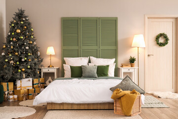 Fototapeta premium Interior of bedroom with door, Christmas tree and glowing lamps