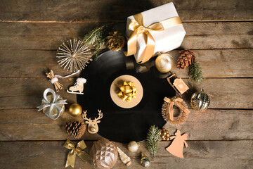 Vinyl disc with Christmas decorations, gift box and fir branches on wooden background