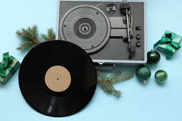 Vinyl record player with disc, Christmas balls, fir branches and gift boxes on blue background