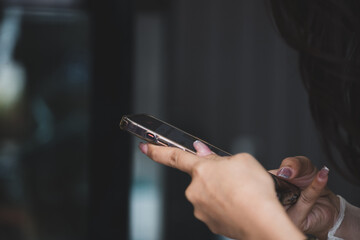 Young woman hand holding cell phone in department store. She was reading and answering emails and shopping online on weekends at shopping mall.