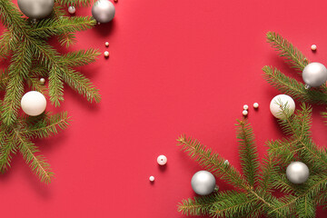 Fir branches with Christmas balls on red background