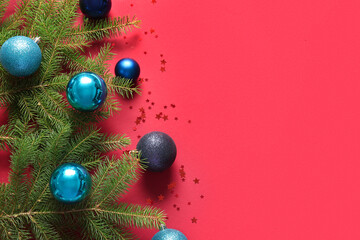 Fir branches with blue Christmas balls and confetti on red background
