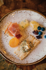 snack plate full of fruits, prosciutto, cheese, crackers, honeycomb from fancy charcuterie board