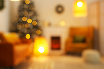 Blurred view of living room with fireplace, Christmas tree and glowing lamps in evening