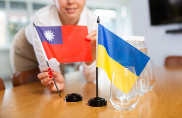 Preparation for international negotiations. Young woman setting national flags of Ukraine and...