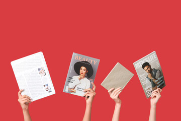 Female hands with different magazines, newspaper and book on red background