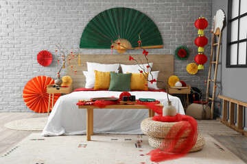 Interior of bedroom with bed, tables and decor for Chinese New Year celebration