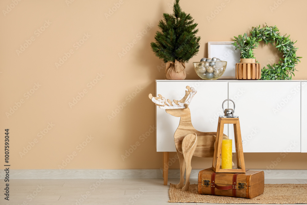 Sticker Christmas lantern with candle on suitcase and wooden deer near chest of drawers with Christmas decorations in room