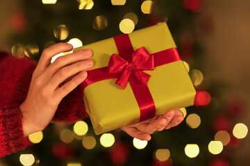 Woman giving gift box on Christmas eve at home, closeup
