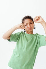 Fierce determination young boy in green t shirt clenches fists in a trendy pose