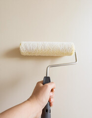 Obraz premium Male hand painting wall with paint roller. Painting apartment, renovating with white color paint 