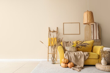 Yellow sofa, pumpkins, pampas grass and plaid in autumn interior of living room