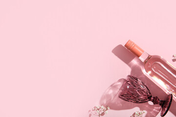 Bottle of tasty pink wine with glass and beautiful gypsophila flowers on color background