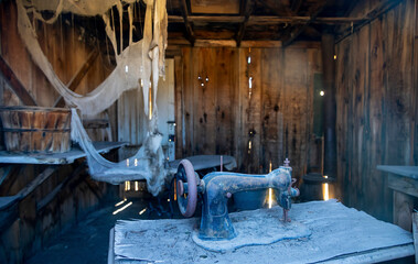An abandoned antique sewing machine sits in a dilapidated wooden shack at Bodie State Historical...