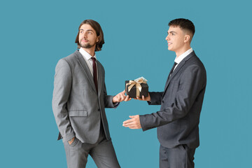 Young business men with gift box on blue background. Corruption concept