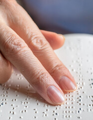 Close up of visually impaired or blind person reading Braille with hand. World Braille Day
