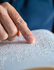 Hand of a blind person reading some braille text touching the relief. Empty copy space for Editor's content.
