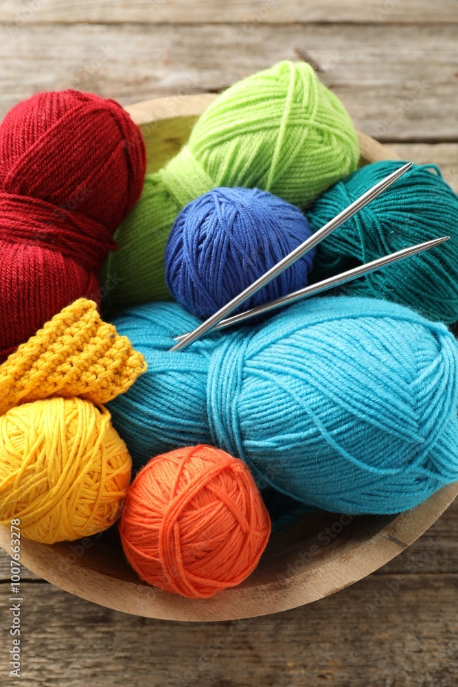 Poster Different yarns, knitting needles and pattern sample in bowl on wooden table, above view