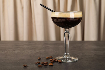 Fresh coffee cocktail in glass and beans on grey table. Space for text