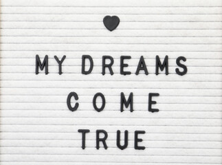 Letter board with phrase My dreams come true as background, top view