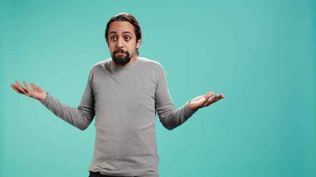 Man shrugging shoulders, unable to provide answer, having detached apathy facial expression. Apathetic person doing hand gesturing showing lack of knowledge, studio background, camera B