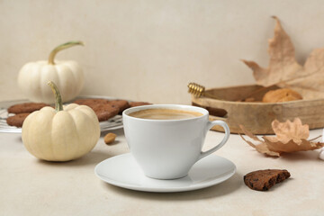 Cup of tasty pumpkin coffee with autumn decorations and cookies on white grunge background