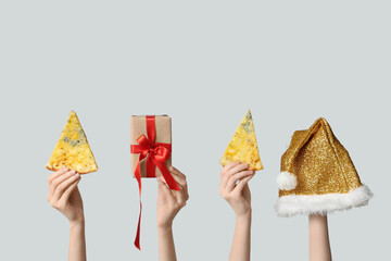 Female hands with pizza slices, Santa hat and gift box on white background