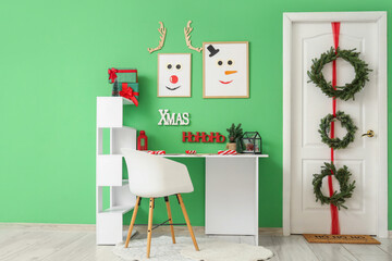 Interior of Christmas hallway with decorated door, gift boxes and workplace near green wall