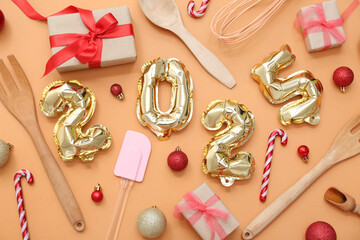 Figure 2025 with cooking utensils and Christmas balls on orange background