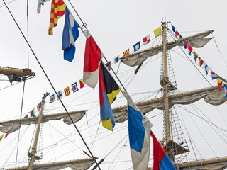 Navy day holiday background of sailing ship mast with colorful flags on rigging ropes