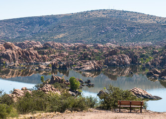 A wooden bench overlooking Watson Lake in Prescott, Arizona, USA on sunny summer day