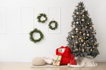 Interior of light room with Santa bag, Christmas tree and wreaths