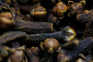 A close-up texture of freshly dried clove spices scattered on the ground. Cloves serve as a dried herb for food flavoring and natural medicine. Dry Organic Clove Spice.