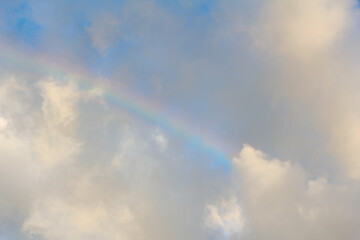 Rainbow and clouds on sky at sunset
