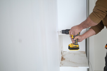  using electric drilling on white wooden board 