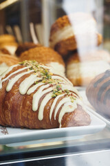 vertical shot of fresh baked croissant in a glass transparent container at shop 