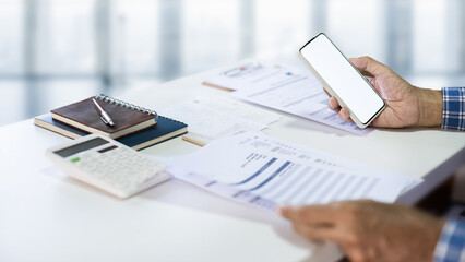 Asian man hand using mobile phone start doing online business, checking financial and business document, bank statement after start new business owner and evaluate business performance