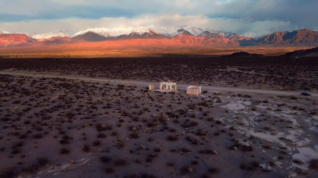 Derelict house in the desert with the snowcapped Andes in the distance. Aerial view, drone flyby.