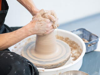Close-up of a potter's hands working on a pottery wheel. 