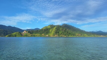 Beautiful view of hills with blue and cloudy skies. The Picture was taken fraom the midle of the sea. Mandeh, West Sumatra, Indonesia