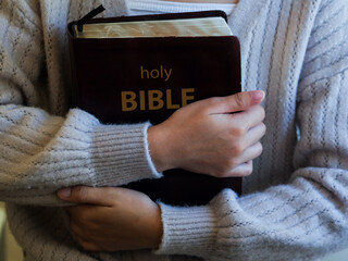 Christian woman is holding and hugging the bible representing a symbol of hope and salvation from the Lord. The concept for faith, spirituality, and religion.