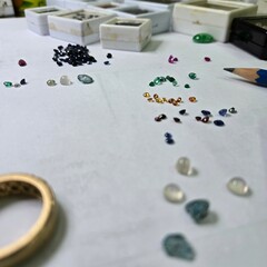 loose stones as ruby, emerald, blue sapphire or etc. there is a gold ring setting on white paper...