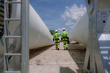 Maintenance engineer team standing at windmills at wind turbine farm. Group of people wear safety helmet and uniform working at alternative renewable energy wind station. Sustainable energy technology © Nassorn